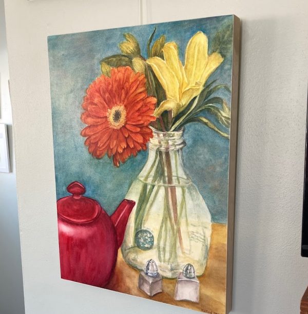 An original watercolor painting of a gerbera daisy and red teapot mounted on cradled board and sealed with wax